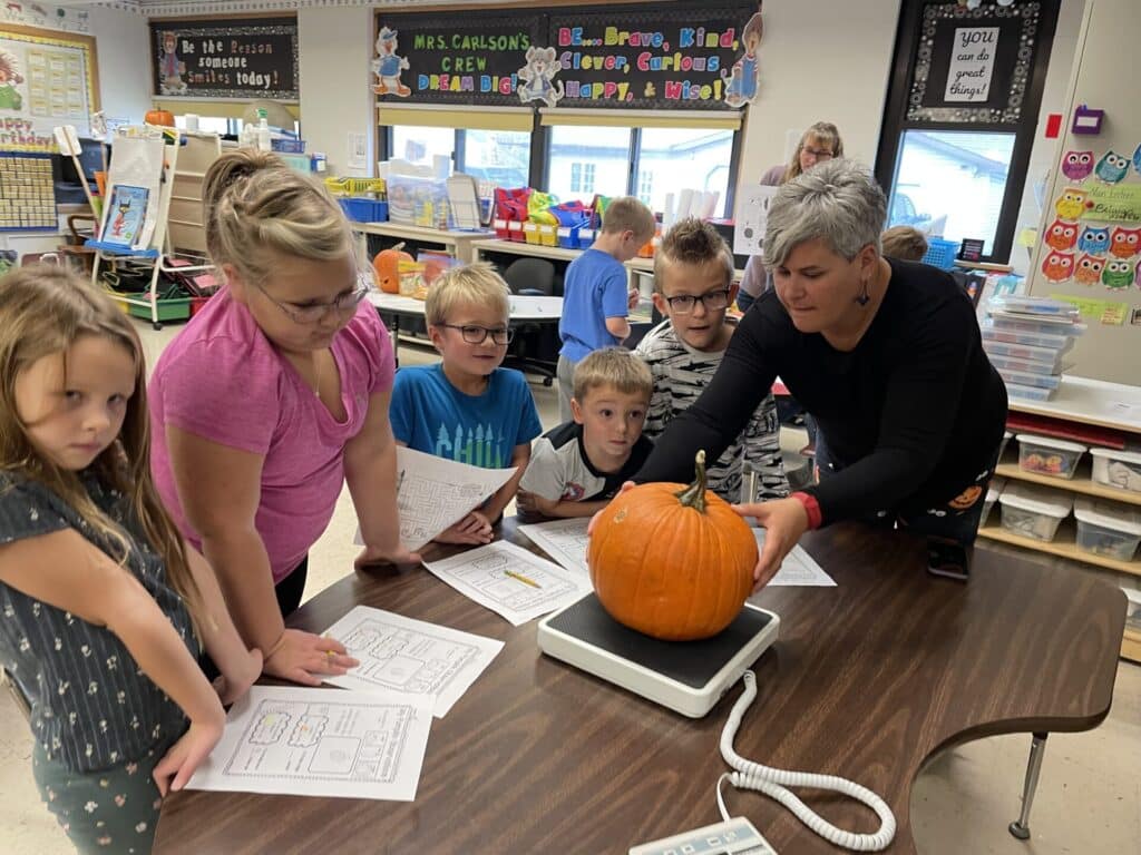 A Group Of Children Are Exploring A Pumpkin On A Table Using Curriculum Resources