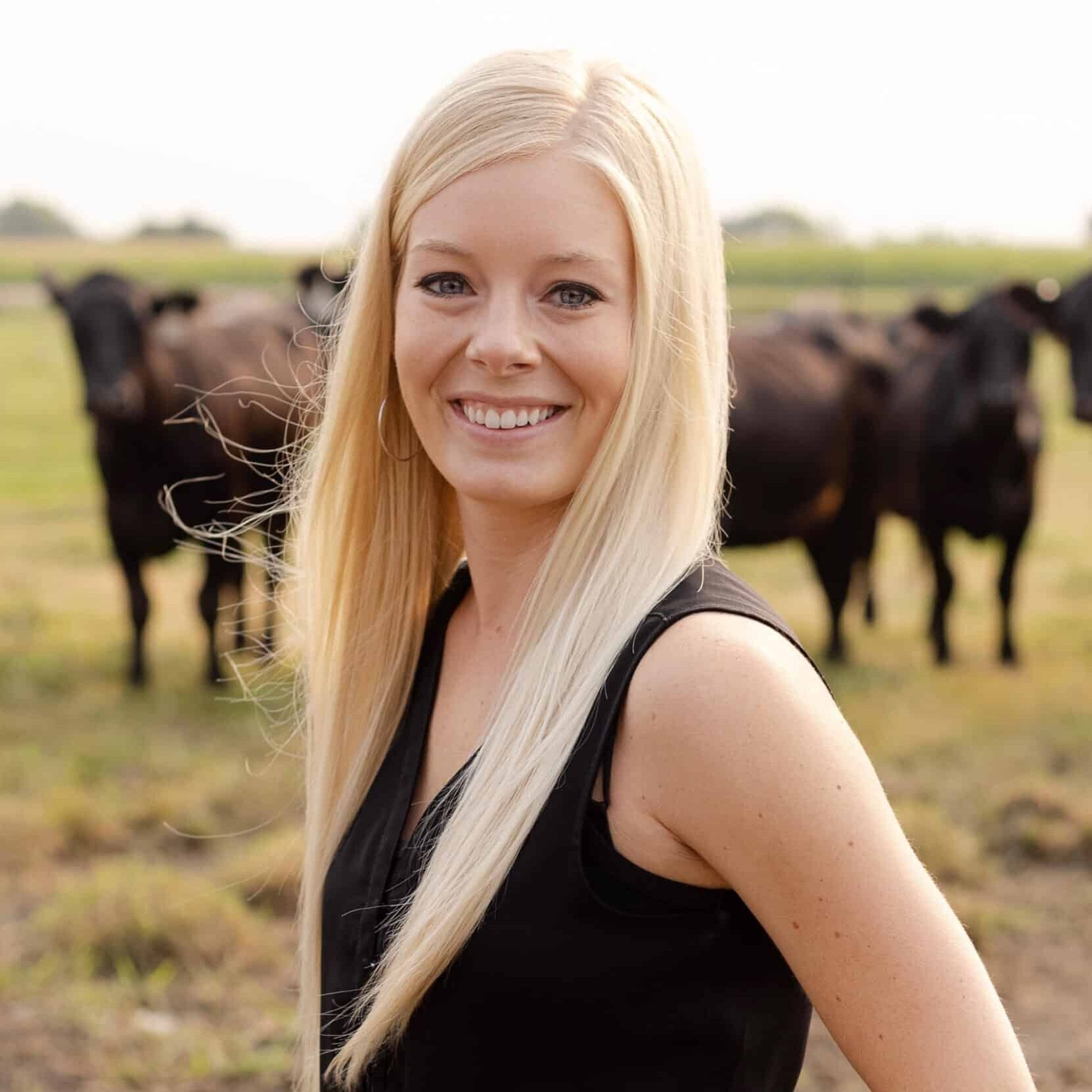 Haley Ammann Ekstrom standing in front of cows.