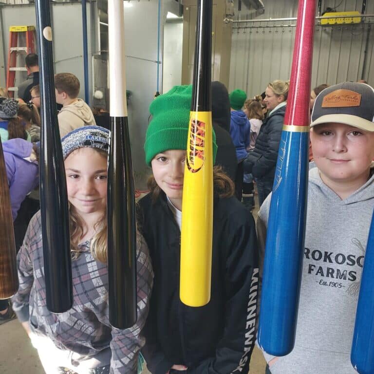 A Group Of People Standing In Front Of A Display Encouraging Others To Make A Donation Towards Baseball Bats
